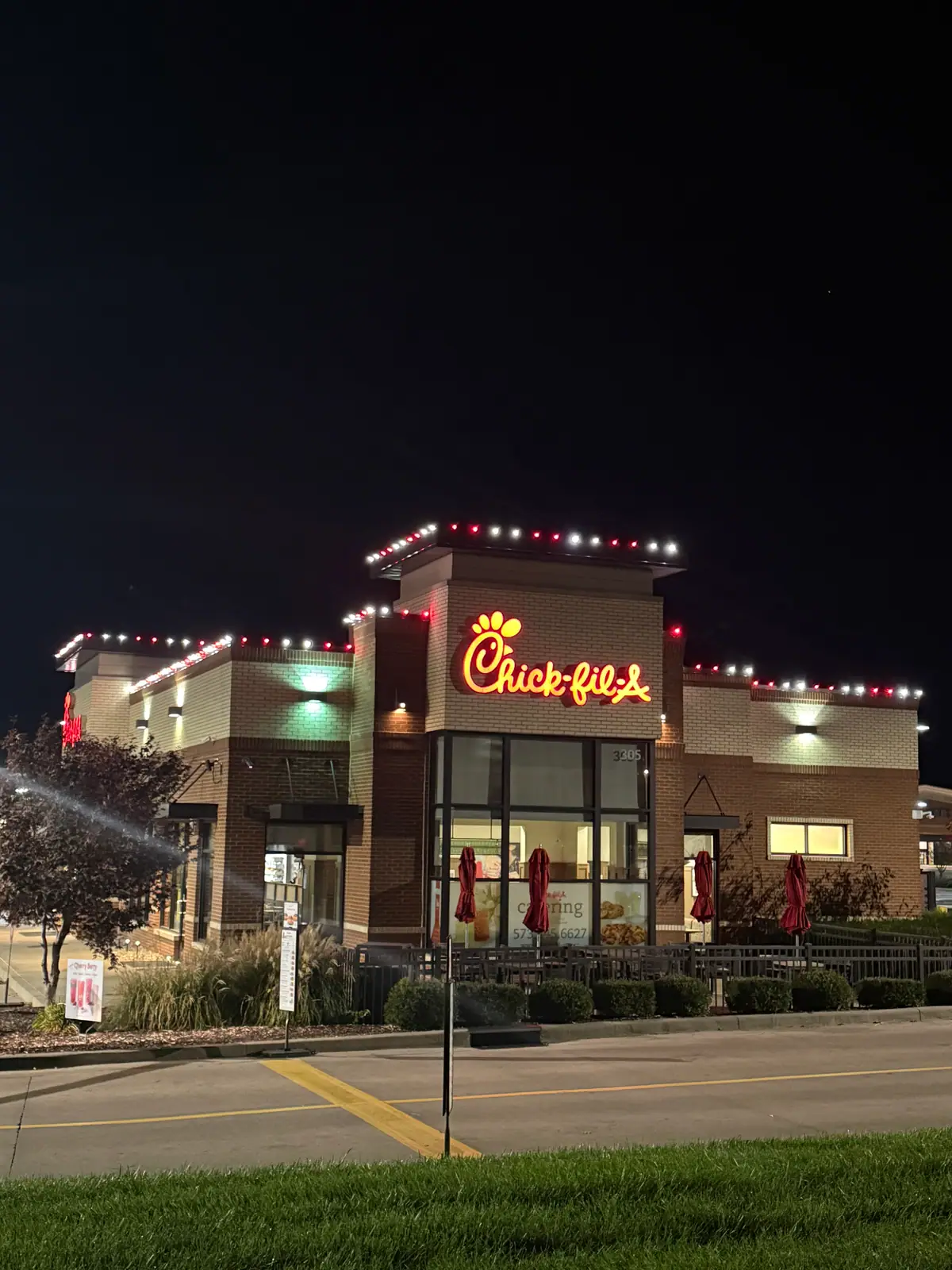 A restaurant storefront outlined in warm white and red lights along the parapet