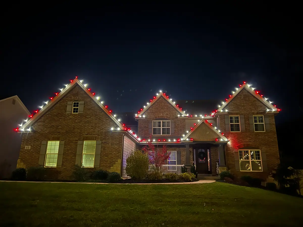 A brick home trimmed in red and warm white along the rooflines and gables